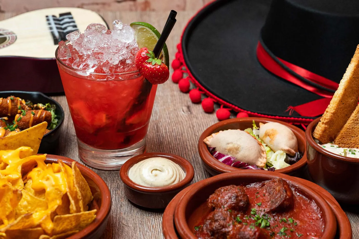 Een aardbeienmojito tussen schaaltjes nacho's, stoofvlees en dipsauzen